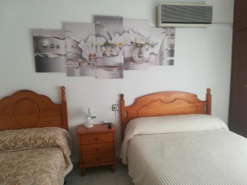 马萨龙港Pension La Linea的一间卧室设有两张床,墙上配有电视。