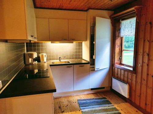 希塞里贝克Klarälvsbyn的厨房配有白色橱柜、水槽和窗户。