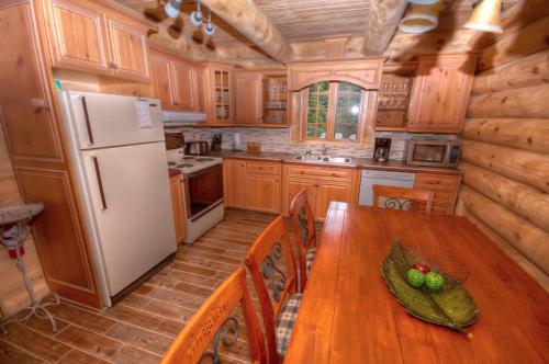 Saint-Tite-des-Caps圆木流度假屋的厨房配有木桌和冰箱。