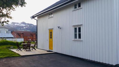 斯沃尔韦尔Svinøya, hyggelig leilighet的白色的建筑,设有黄色的门和桌子