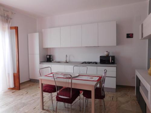 特拉佩托SOPHIA Appartament的厨房配有桌椅和白色橱柜。