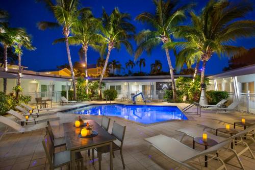 基韦斯特Orchid Key Inn - Adults Only的一个带桌椅的度假村游泳池,并种植了棕榈树