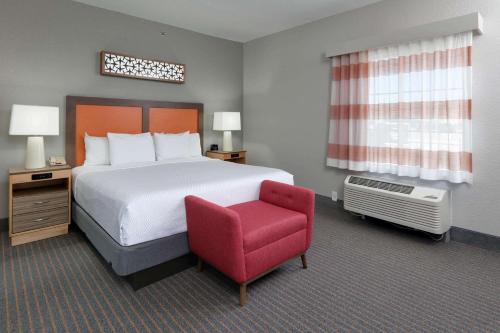 达拉斯达拉斯爱之田拉金塔旅馆及套房的酒店客房,配有一张床和一张红色椅子