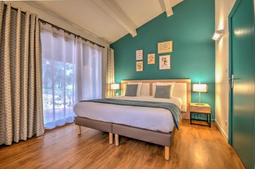 普罗旺斯地区萨隆Best Western Domaine de Roquerousse的一间卧室配有一张蓝色墙壁的床和一扇窗户