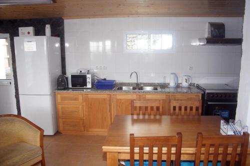São MateusRetiro dos Cabritos的厨房配有木桌和白色冰箱。