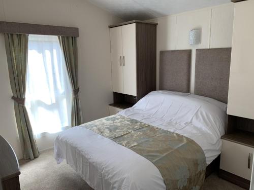 罗斯伯里Riverside Rothbury Superior Lodge的一间卧室设有一张大床和一个窗户。