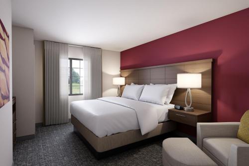 夏洛茨维尔Staybridge Suites Charlottesville Airport, an IHG Hotel的酒店客房带一张大床和一把椅子