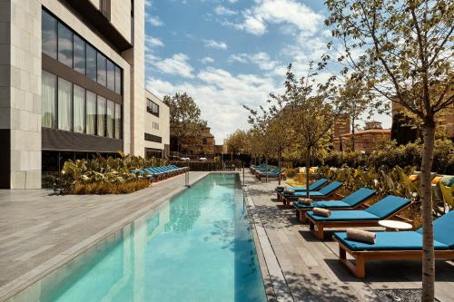巴塞罗那Grand Hyatt Barcelona的一座带躺椅的游泳池位于大楼旁