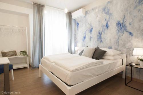 乌迪内Sleep In Udine的卧室配有白色床,墙上挂有蓝色画作