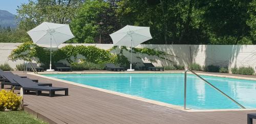 AlcedaHotel Balneario De Alceda的一个带两把遮阳伞和椅子的游泳池以及一个游泳池