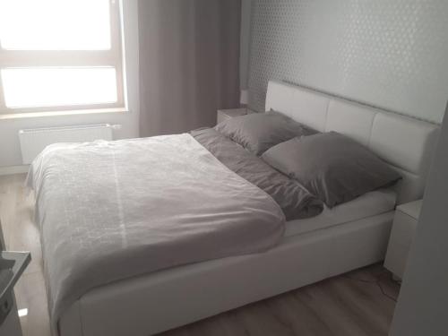 格但斯克Apartament Nowa Letnica的白色卧室内的一张白色床,设有窗户
