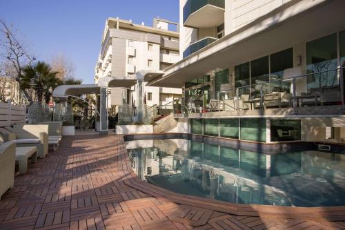 里米尼Best Western Maison B Hotel的一座大型建筑,毗邻一座建筑,设有游泳池