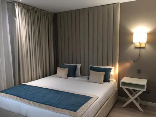 萨兰HOTEL LES 3 VALLÉES的一间卧室配有一张带蓝色枕头的大床