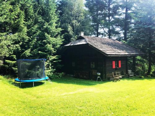 雷丹尼茨恩Cozy Log Cabin near Faaker See的小屋,草地上摆放着蓝色椅子
