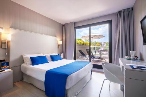 马略卡岛帕尔马艾斯拉马略卡酒店&温泉的酒店客房设有一张床和一个带遮阳伞的阳台