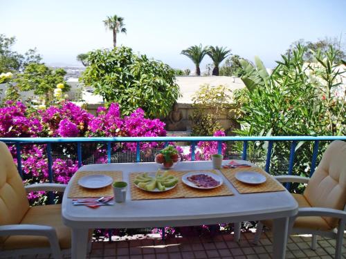 阿罗纳Casa Limona - In Teneriffas Sonnigem Süden的紫色花阳台上带食物的桌子