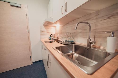 奥斯威辛Villa Centro的厨房配有不锈钢水槽和白色橱柜