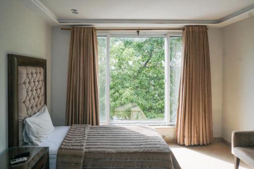 拉合尔城景酒店及餐厅的一间卧室设有一张床和一个大窗户