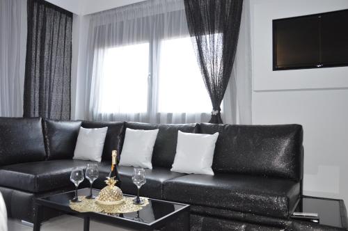 尼亚·卡利克拉提亚S. Luxury Princess Suite的客厅里一张带酒杯的黑色皮沙发