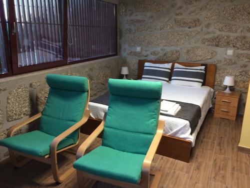 VilarinhoCasa Campos的一间卧室配有一张床和两张绿色椅子