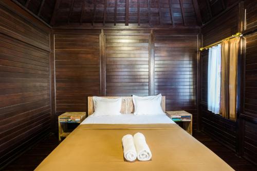 蓝梦岛蓝梦岛阿贡简易别墅宾馆的木制客房的一张床位,配有两个枕头