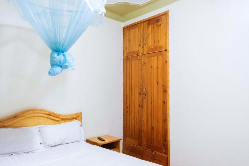 MbalePalm Hotel的一间卧室配有一张床和一个木制橱柜