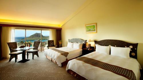 垦丁大街垦丁福华渡假饭店的酒店客房设有两张床、一张书桌和一个窗户。