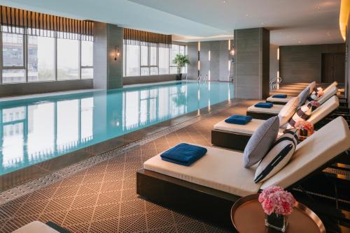 上海上海卓越铂尔曼大酒店的一间酒店客房内的游泳池,有一排床