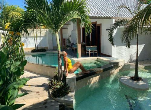 吉利特拉旺安The White Key Luxury Villas的坐在棕榈树旁的游泳池里的人