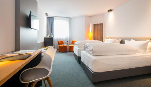伍珀塔尔Flemings Hotel Wuppertal-Central的酒店客房配有两张床和一张书桌