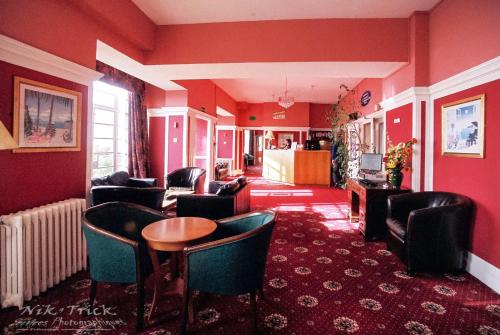 福克斯通南崖酒店的客厅设有红色的墙壁、椅子和桌子
