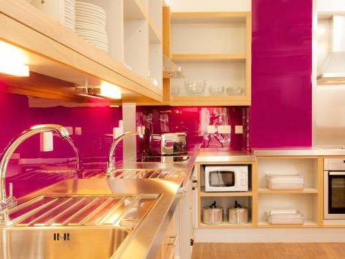 埃文河畔斯特拉特福YHA埃文河上游斯特拉特福德酒店的厨房设有紫色墙壁和不锈钢水槽