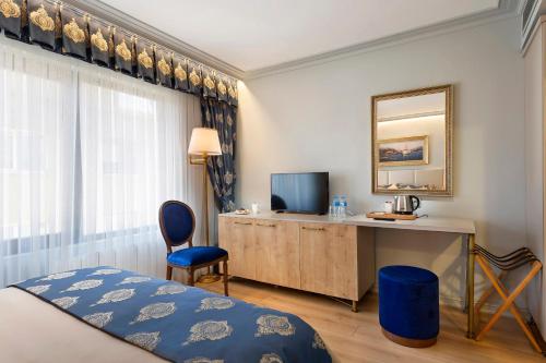 伊斯坦布尔Güner Business Hotel的酒店客房配有一张床、一张书桌和一台电视。