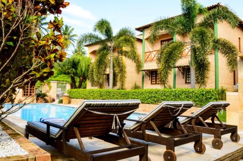 帕拉库鲁Hotel Vento Brasil的两把躺椅和一个位于房子前的游泳池