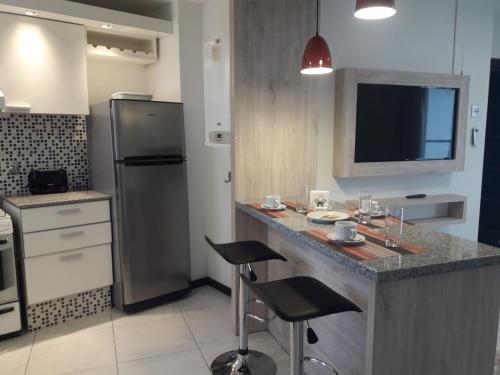 里奥夸尔托Departamento Torre Sofitel的厨房配有带凳子的柜台和冰箱。