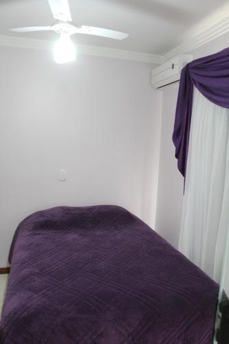皮拉图巴Apartamentos Morada do Sol的一间卧室配有紫色的床和吊扇
