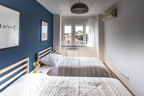 萨格勒布Blue Sky Apartment的卧室设有两张床铺和蓝色的墙壁