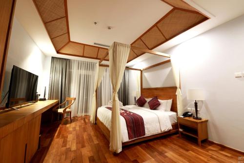 美娜多NDC Resort & Spa的一间卧室配有一张天蓬床和一台电视机