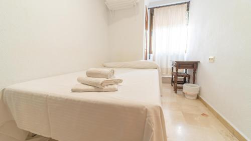 格拉纳达博卡内格拉旅舍的白色客房内的两张床和毛巾