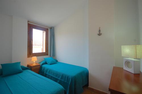 滨海托萨Lets Holidays Heart of Tossa Apartment的一间卧室设有两张蓝色的床和窗户