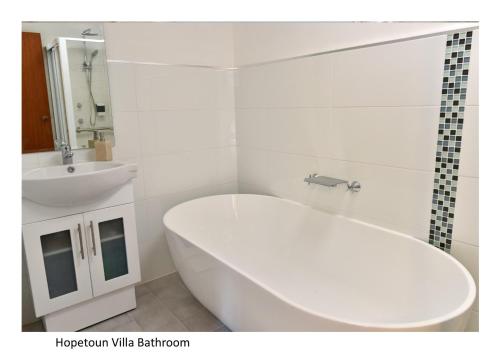 Woonona霍普顿别墅的白色的浴室设有浴缸和水槽。