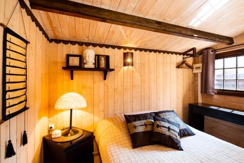 拉卡诺VILLA ZENITH Hostel - LA MAISON的卧室配有一张床铺,位于带木墙的房间内