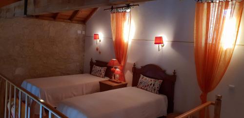 LamasCasa Rustica do Lagar的配有两张床和橙色窗帘的房间