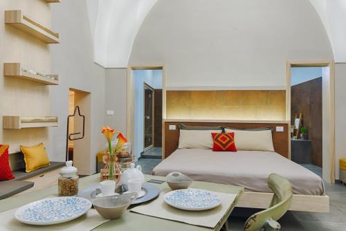 梅萨涅Sacratum B&B Suite Spa的一间卧室配有床和一张桌子,上面有盘子