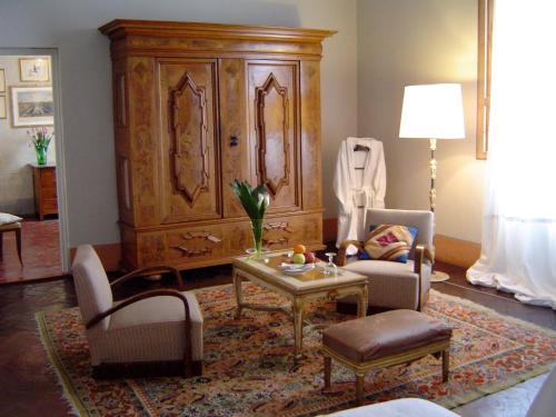 佛罗伦萨勒翠斯坦兹酒店的客厅配有两把椅子和大型木制橱柜