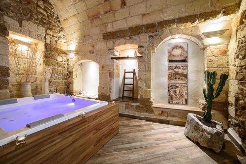 梅萨涅Sacratum B&B Suite Spa的石墙内大浴缸的大浴室