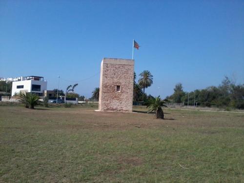 巴里亚纳Casa Ferrada的一块砖塔,上面有旗帜,在田野里