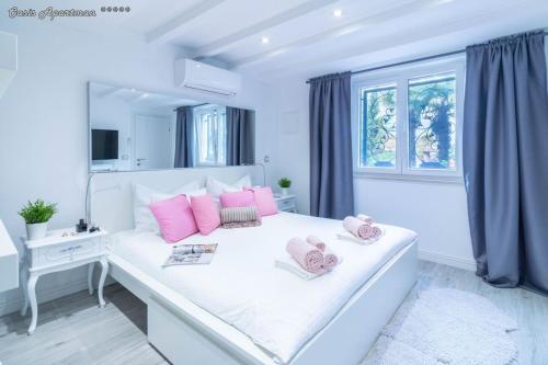 奥帕提亚Oasis Apartments Opatija的白色卧室,床上配有粉红色枕头