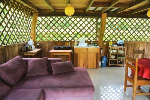 卡维塔Hotel & Cabinas Nadine的一间带紫色沙发的客厅和一间厨房