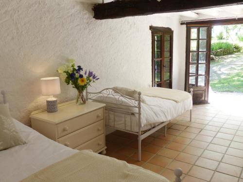米雷普瓦Hameau de Montcabirol - Foix的一间卧室设有两张床和一张花瓶桌子。